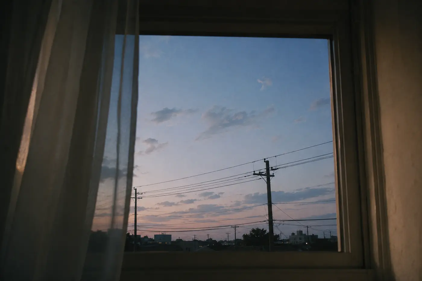 a quiet window at twilight with sky, power lines, and soft curtains